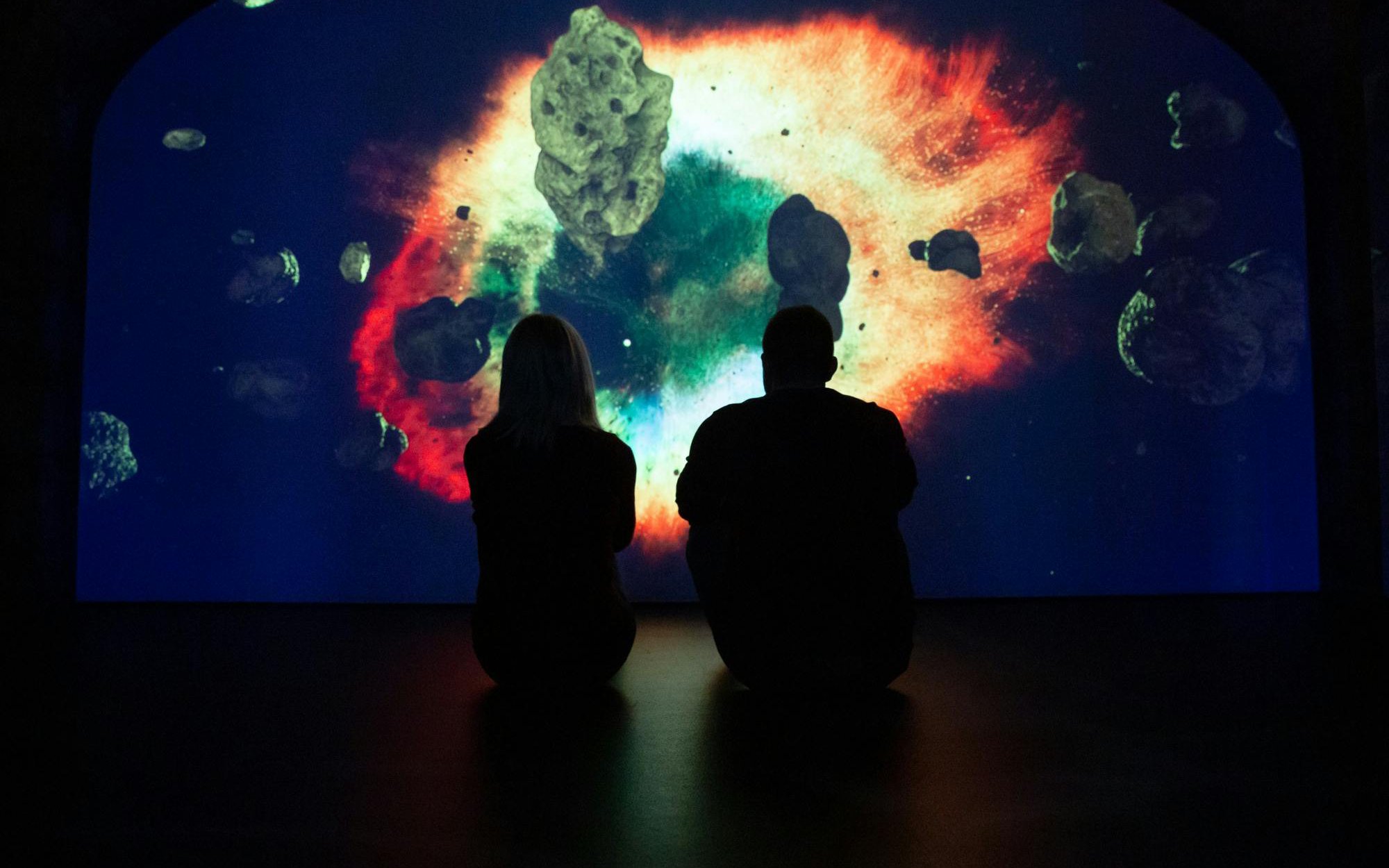 Visitors observing a cosmic display at the epic museum exhibit.