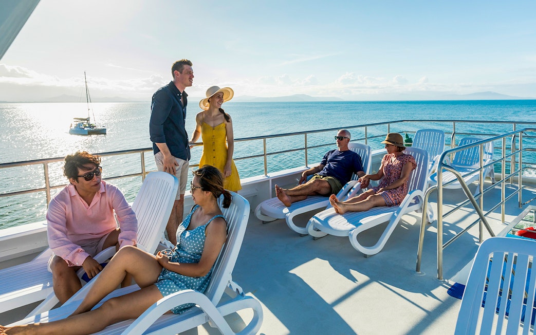 Guests relaxing on cruise ship deck overlooking the Great Barrier Reef, Australia.