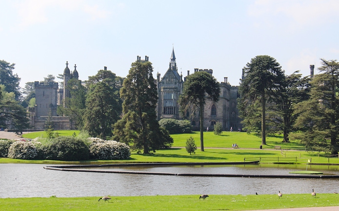 Exteriors of Alton Towers with lush gardens and a serene pond in the foreground.