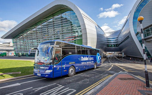 Blue Dublin Express bus departing Dublin Airport terminal.
