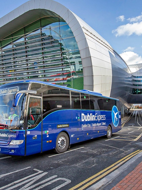Blue Dublin Express bus departing Dublin Airport terminal.