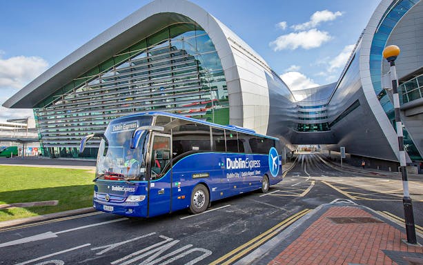 Blue Dublin Express bus departing Dublin Airport terminal.