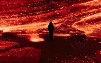 Person experiencing immersive Pompeia exhibit at IDEAL Barcelona with vibrant red visuals.