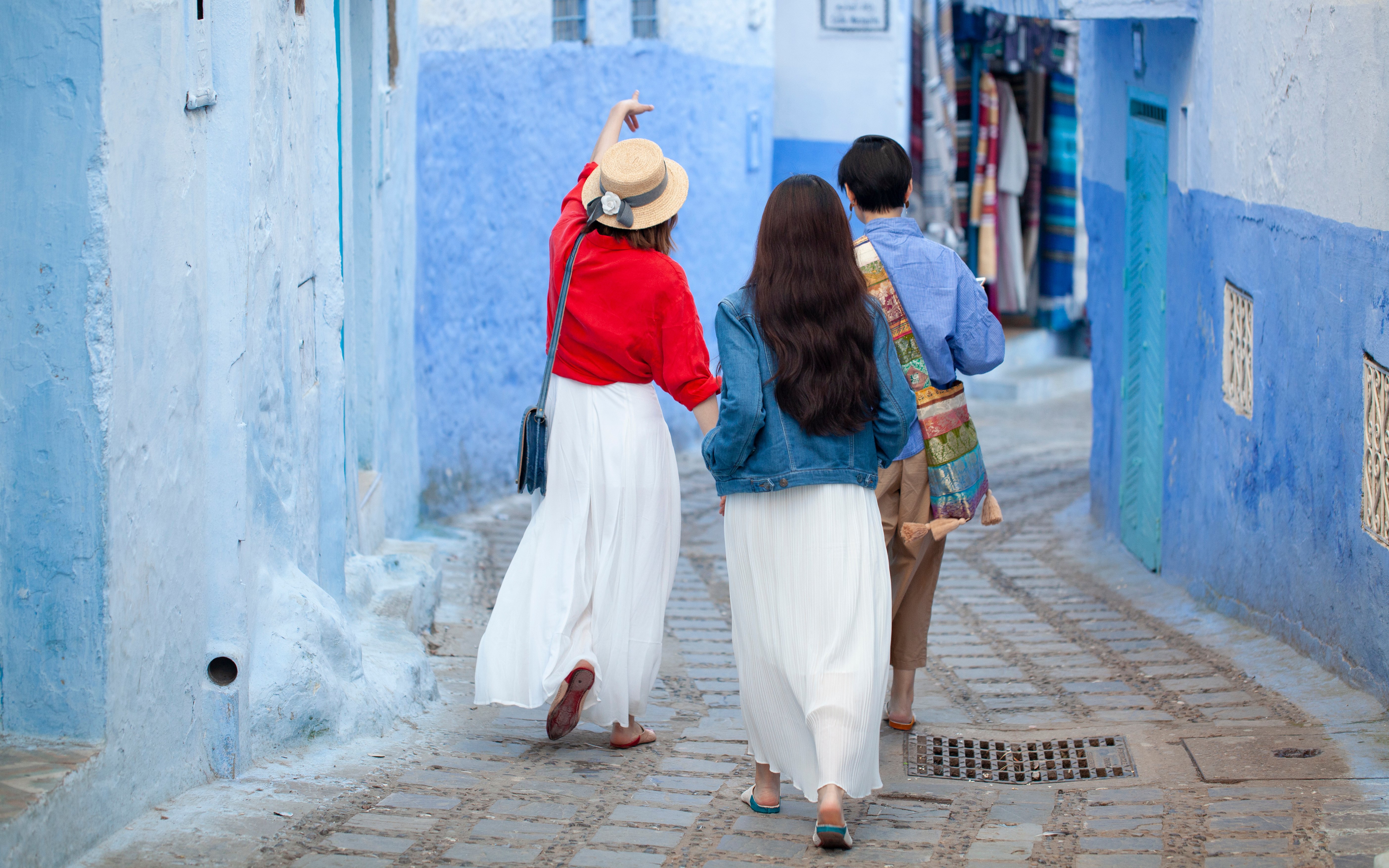 Tourists walking with guide in blue streets of Chefchaouen, Morocco.