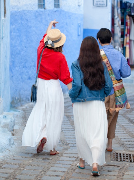 Tourists walking with guide in blue streets of Chefchaouen, Morocco.