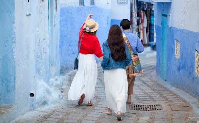 Tourists walking with guide in blue streets of Chefchaouen, Morocco.