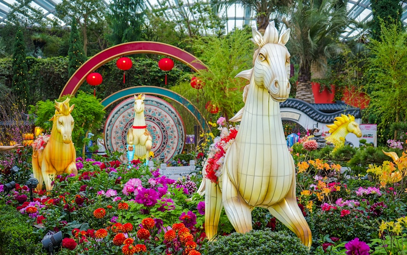Horse lanterns among vibrant spring blossoms at Flower Dome, Gardens by the Bay, Singapore.