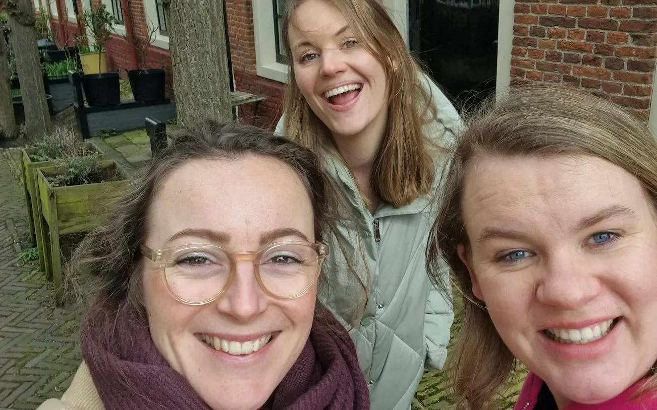 Three people smiling in a courtyard in Haarlem during a self-guided city exploration game.