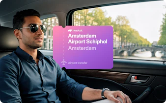 Man in car during Amsterdam airport transfer with canal view.