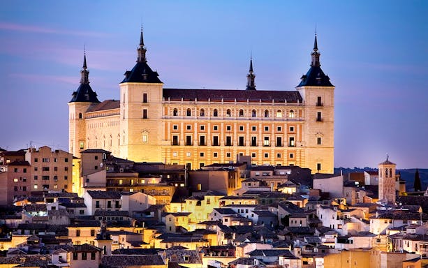 Alcázar of Toledo illuminated at dusk, showcasing the city's historic architecture.