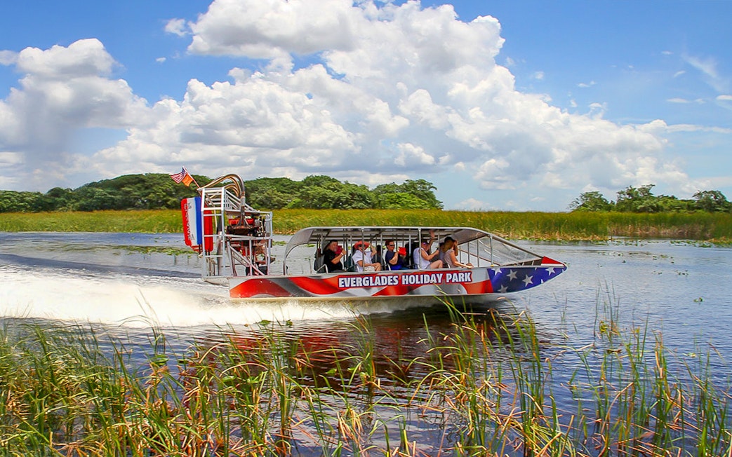 Everglades airboat with tourists gliding through wetlands, Miami tour.