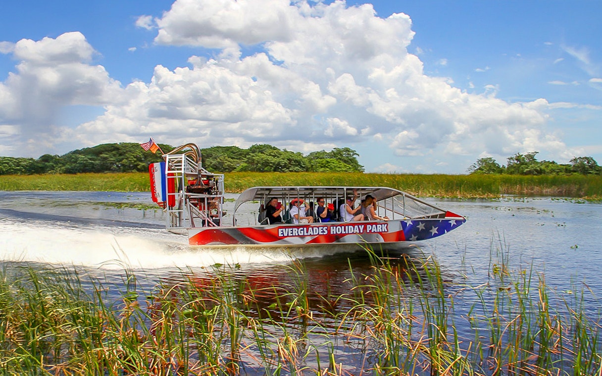 Everglades airboat with tourists gliding through wetlands, Miami tour.