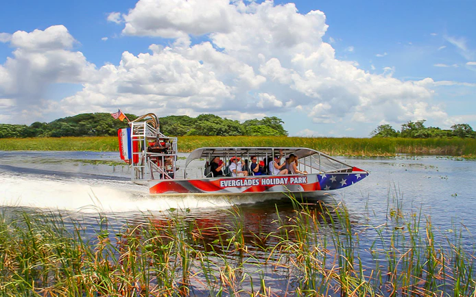 Everglades airboat with tourists gliding through wetlands, Miami tour.