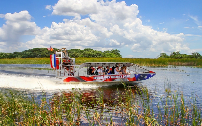 Everglades airboat with tourists gliding through wetlands, Miami tour.