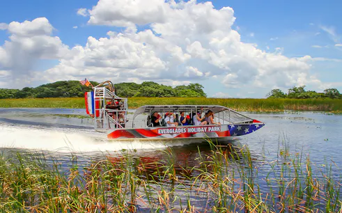 Everglades airboat with tourists gliding through wetlands, Miami tour.