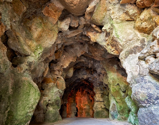 Quinta da Regaleira cave entrance surrounded by lush gardens in Lisbon.