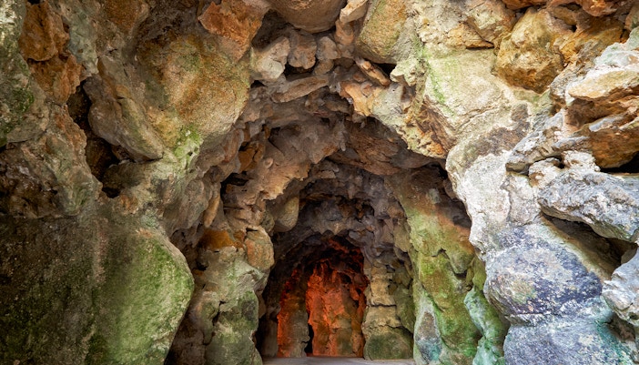 Quinta da Regaleira cave entrance surrounded by lush gardens in Lisbon.