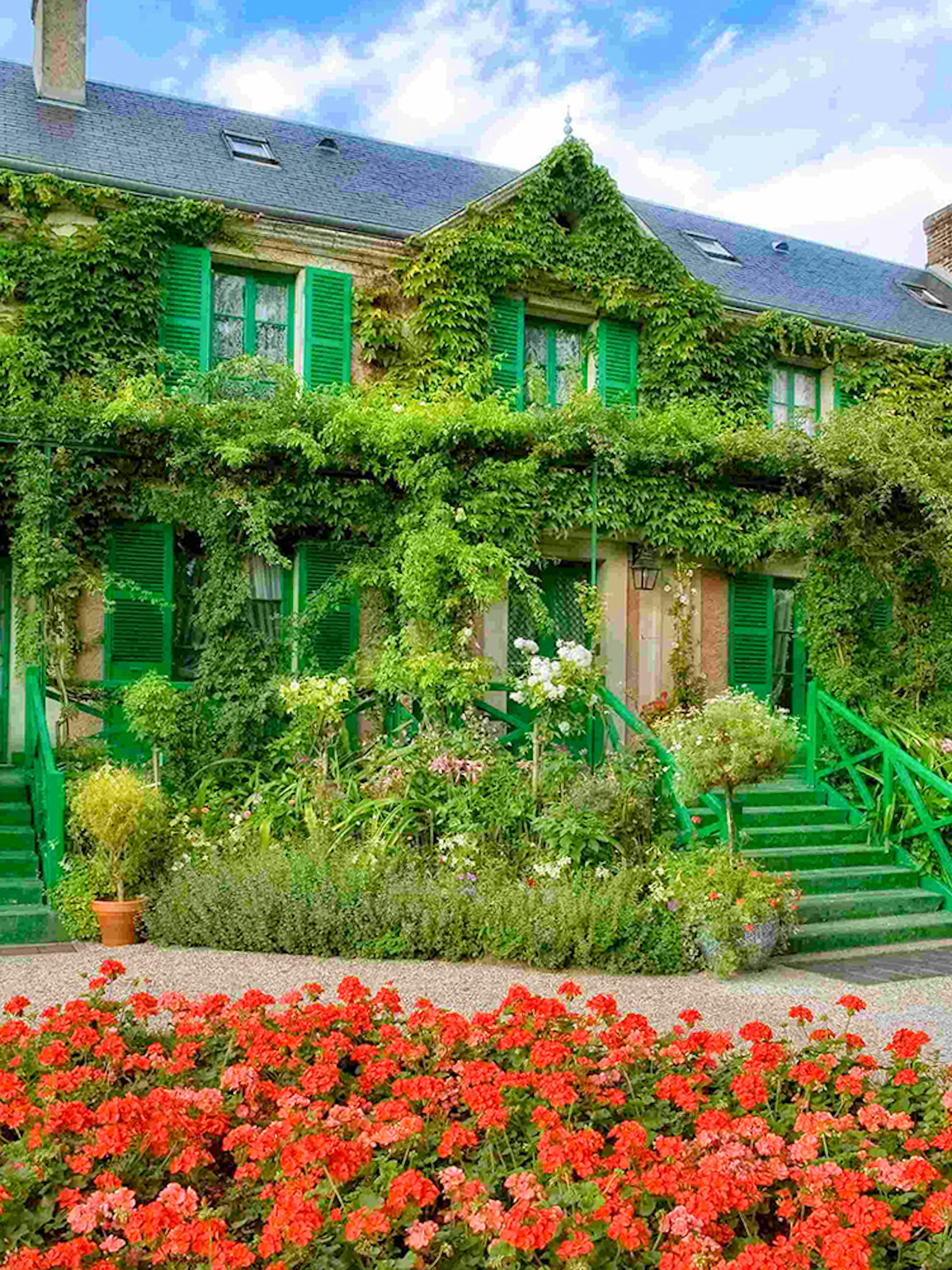 Giverny Gardens with vibrant flowers and ivy-covered house, part of Versailles Palace & Giverny tour.