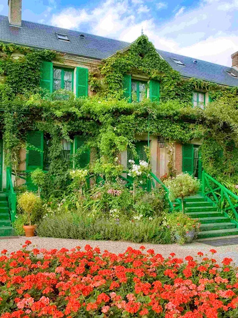 Giverny Gardens with vibrant flowers and ivy-covered house, part of Versailles Palace & Giverny tour.