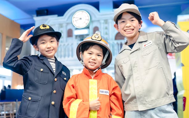 Children in firefighter and worker uniforms at KidZania Tokyo.