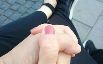 Hands clasped together on cobblestone street, Stockholm city exploration game.