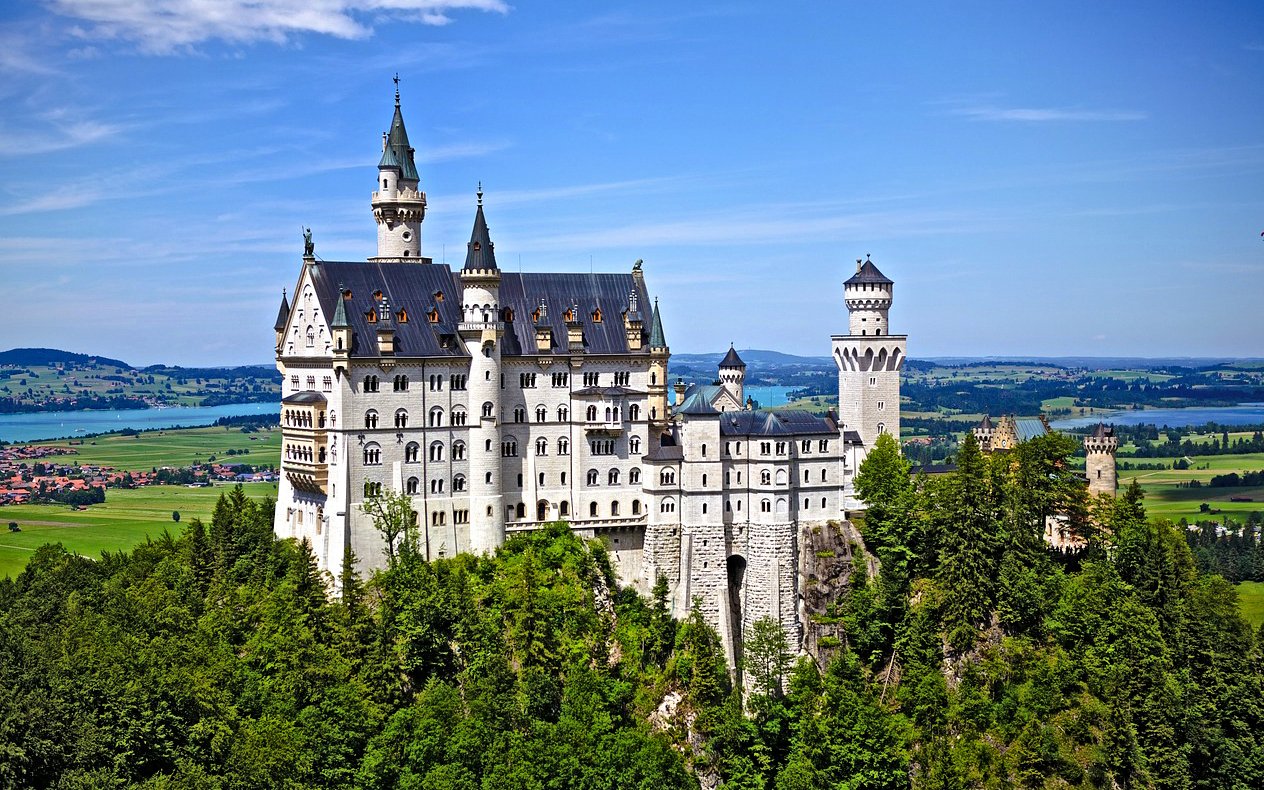 Neuschwanstein Castle in Bavaria, Germany, surrounded by lush green landscape.