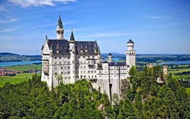 Neuschwanstein Castle in Bavaria, Germany, surrounded by lush green landscape.