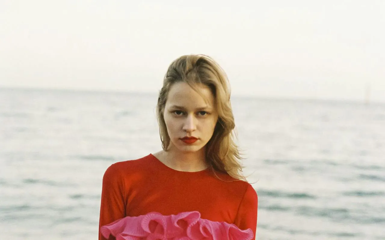 Fashionable individual in red and pink attire by the sea, part of Barcelona luxury boutique tour.