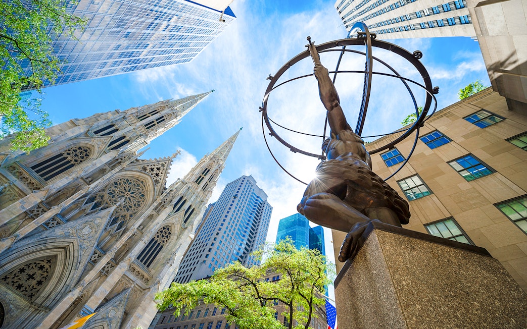 Atlas statue at Rockefeller Center with St. Patrick's Cathedral and skyscrapers in New York City.