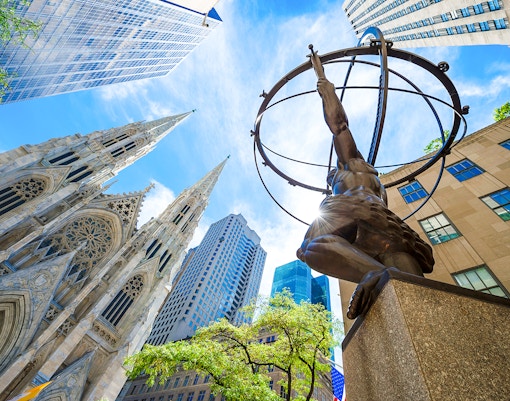 Atlas statue at Rockefeller Center with St. Patrick's Cathedral and skyscrapers in New York City.