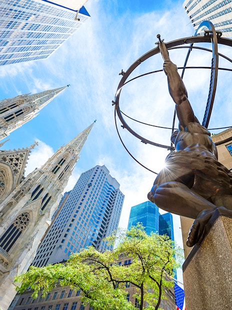 Atlas statue at Rockefeller Center with St. Patrick's Cathedral and skyscrapers in New York City.
