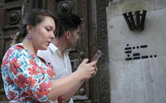 People using a smartphone for a self-guided city exploration game in Rotterdam.