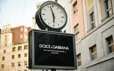 Clock above Dolce & Gabbana store sign on Via Montenapoleone, Milan.