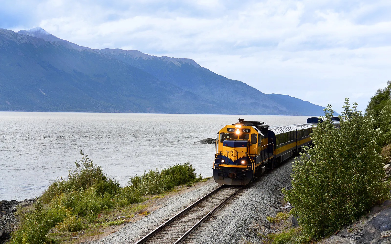 Train on Alaska Railroad by scenic mountain lake.