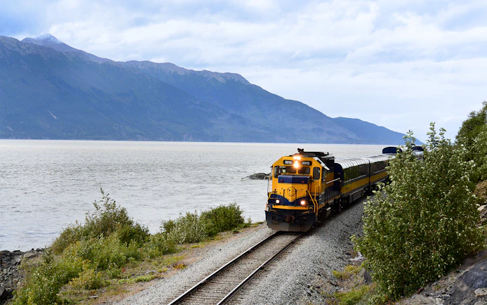 Train on Alaska Railroad by scenic mountain lake.