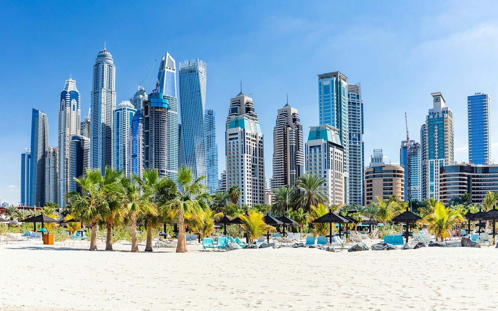 Jumeirah Beach skyline view with tourists enjoying the beach in Dubai, UAE.