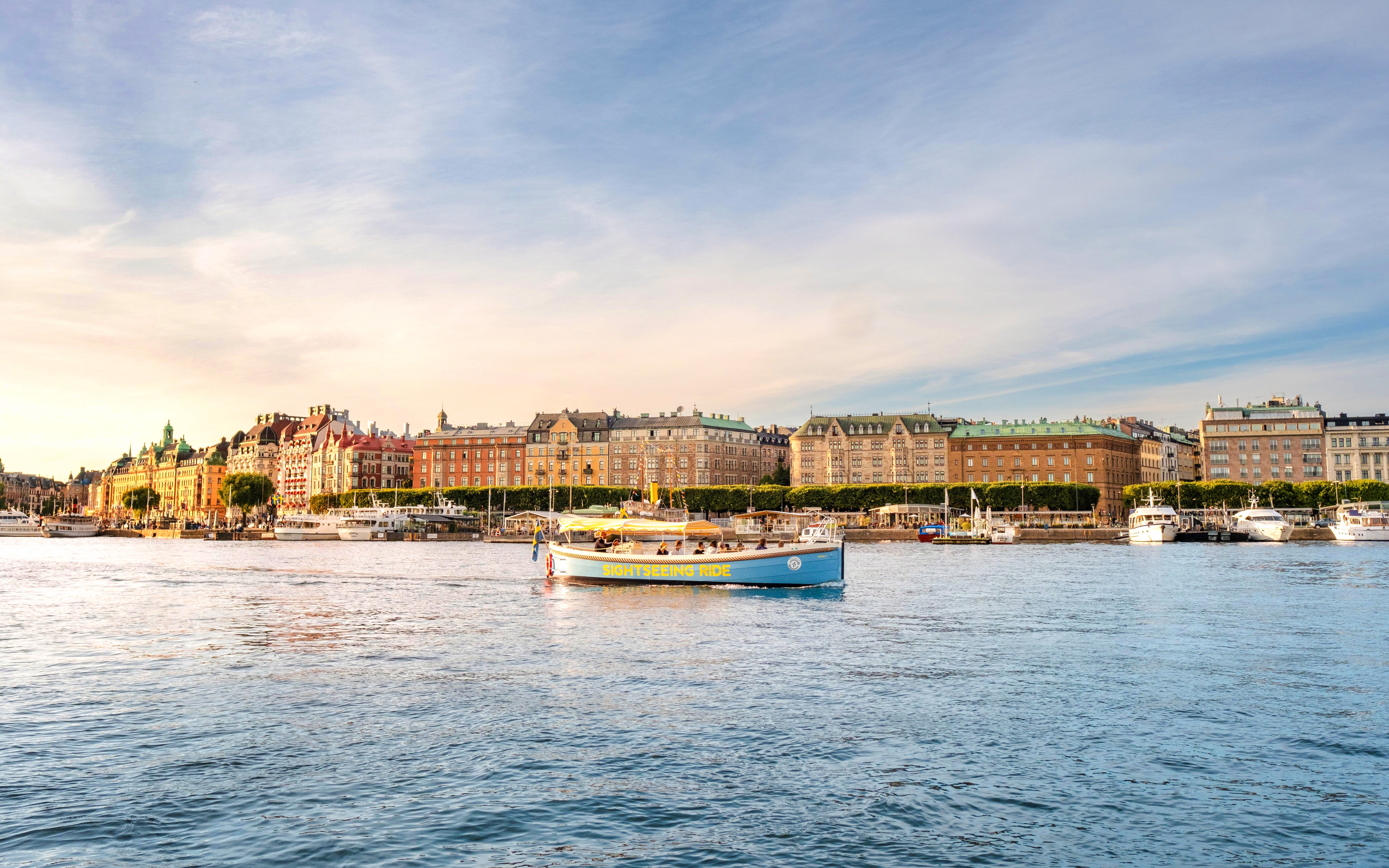 Sightseeing boat on Stockholm waterfront with historic buildings in the background.