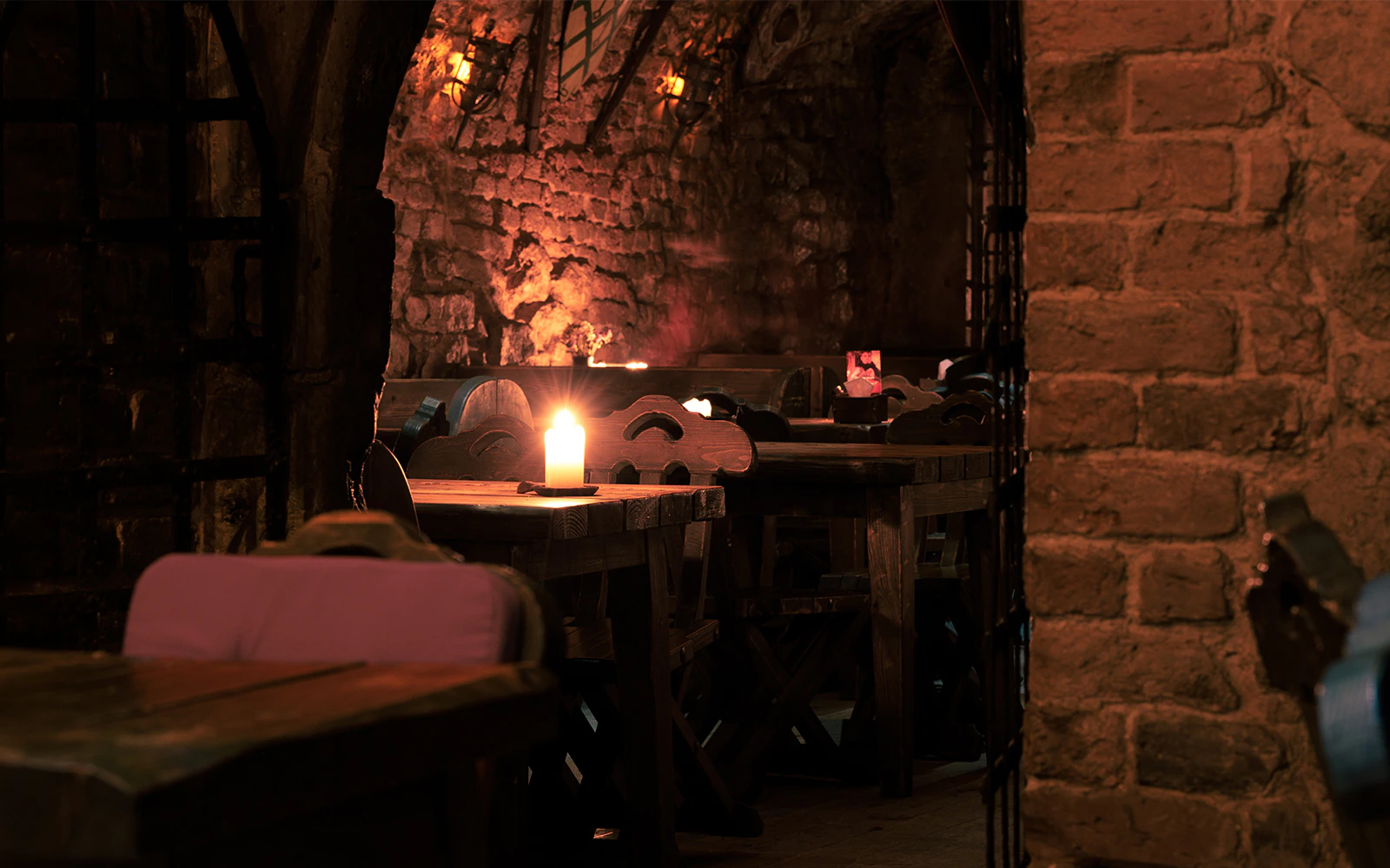 Candlelit underground room with brick walls and wooden tables.