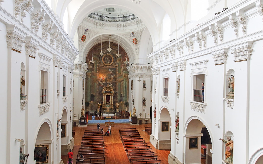 Interior of Jesuit Church in Toledo with ornate altar and wooden pews.