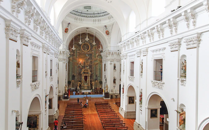 Interior of Jesuit Church in Toledo with ornate altar and wooden pews.