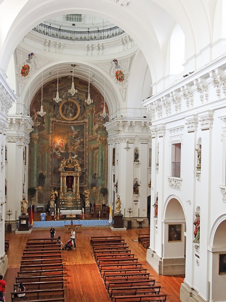 Interior of Jesuit Church in Toledo with ornate altar and wooden pews.