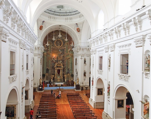 Interior of Jesuit Church in Toledo with ornate altar and wooden pews.