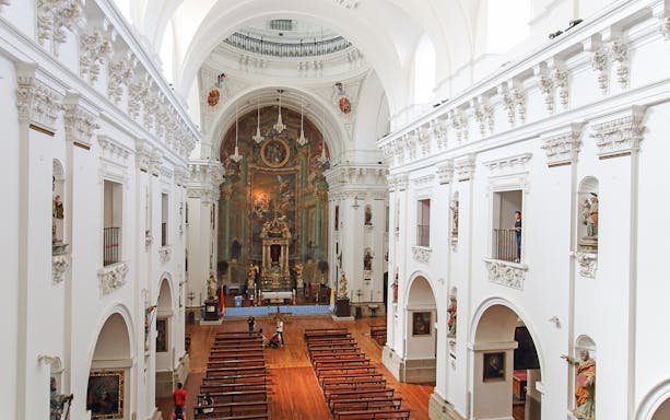 Interior of Jesuit Church in Toledo with ornate altar and wooden pews.