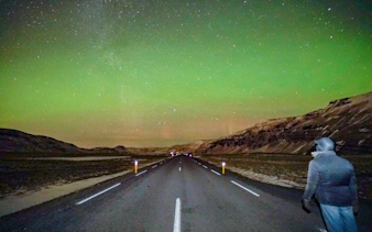 Northern Lights over a road in Iceland during a small-group jeep tour from Reykjavik.