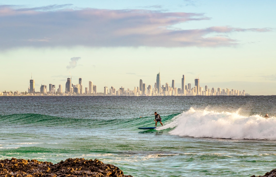 surfer riding on tide in Burleigh Head with the urban skyline of Gold Coast in the background
