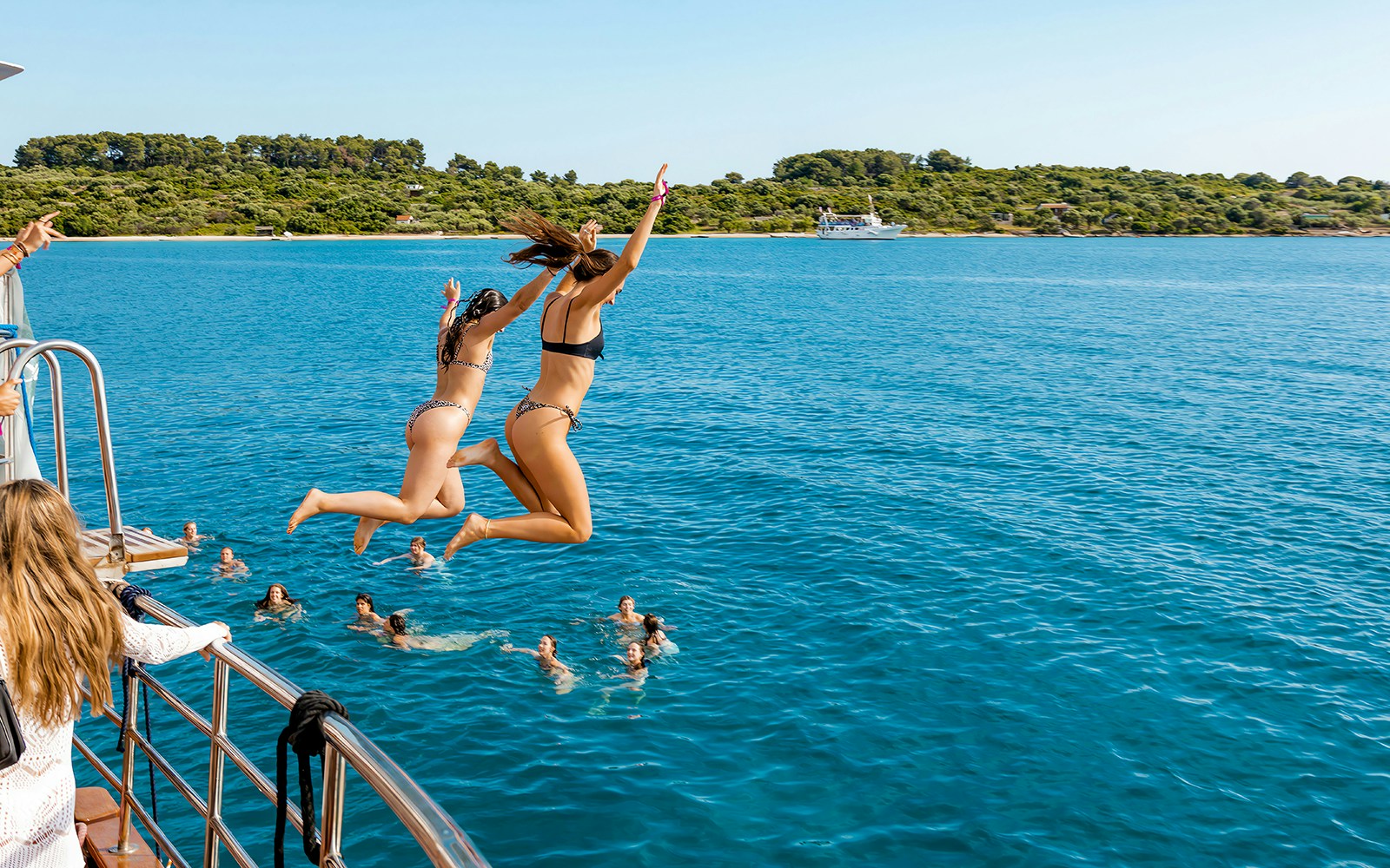 Girls jumping off boat deck into Blue Lagoon during Split, Croatia party.