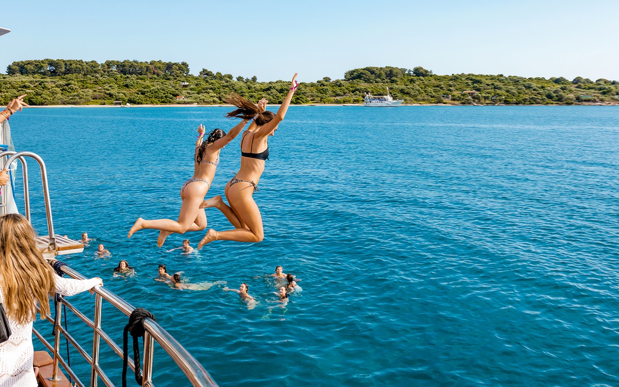 Girls jumping off boat deck into Blue Lagoon during Split, Croatia party.