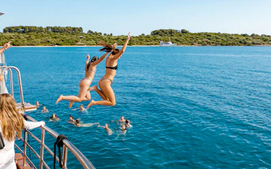 Girls jumping off boat deck into Blue Lagoon during Split, Croatia party.