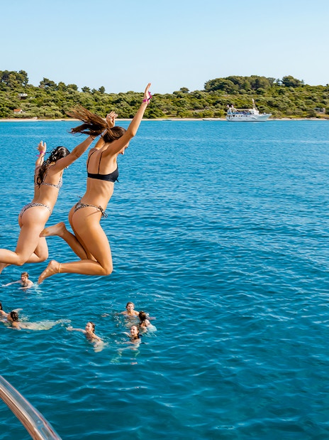 Girls jumping off boat deck into Blue Lagoon during Split, Croatia party.
