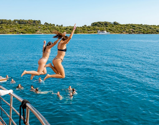 Girls jumping off boat deck into Blue Lagoon during Split, Croatia party.
